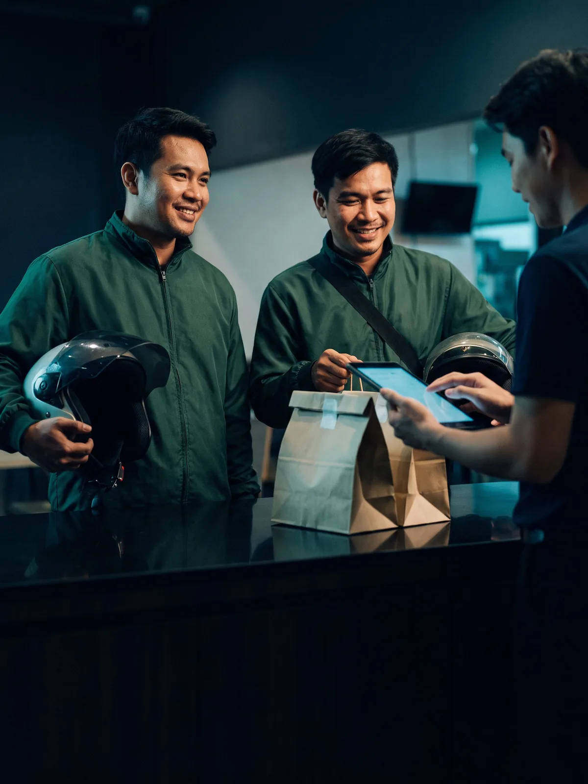 Delivery riders collecting orders at a restaurant pickup counter
